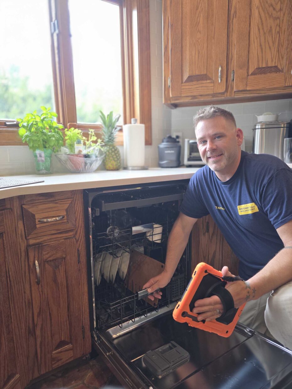 Technician using a cordless tool to repair an open dishwasher
