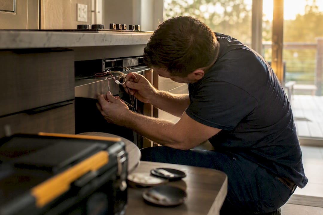 Technician testing induction cooktop wiring