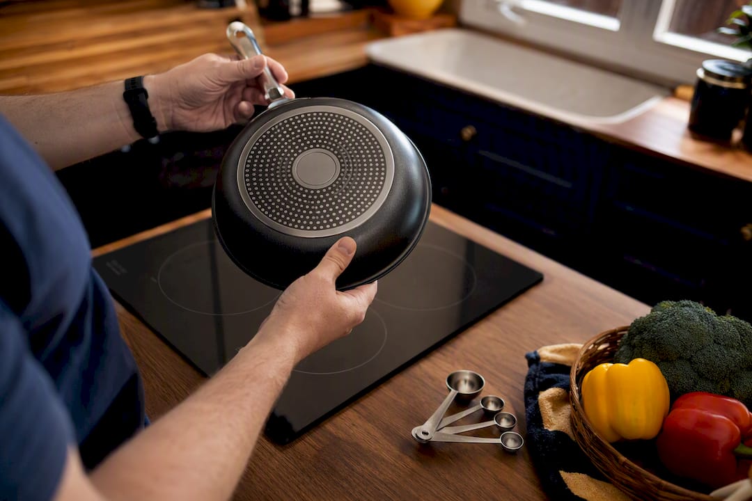Hands holding induction-compatible pan bottom