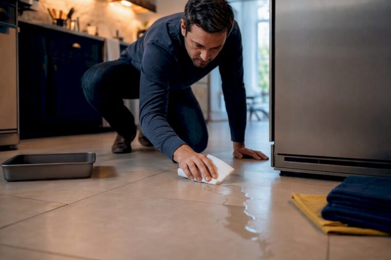 Homeowner tracing water from refrigerator leak