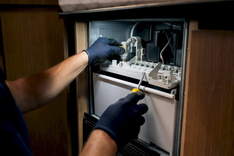 Technician inspecting an ice maker mechanism